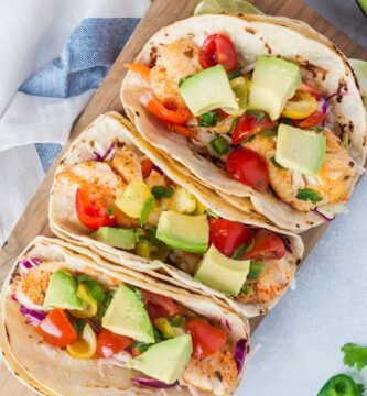 Three fish tacos topped with chunks of avocado.