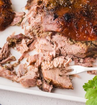 Pork roast cut into slices on a white plate and a fork in one piece.