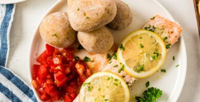 Salmón al horno en un plato cubierto con rodajas de limón