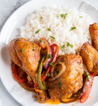 Pollo Guisado servido en un plato con arroz blanco, frijoles y maduros