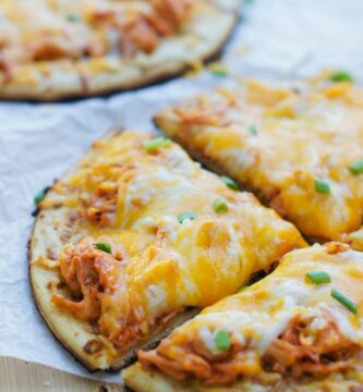 Close up of a buffalo chicken mini pizza garnished with chopped chives.