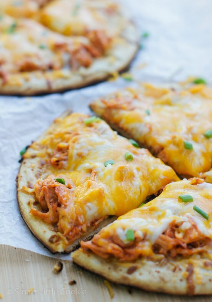 Close up of a buffalo chicken mini pizza garnished with chopped chives.