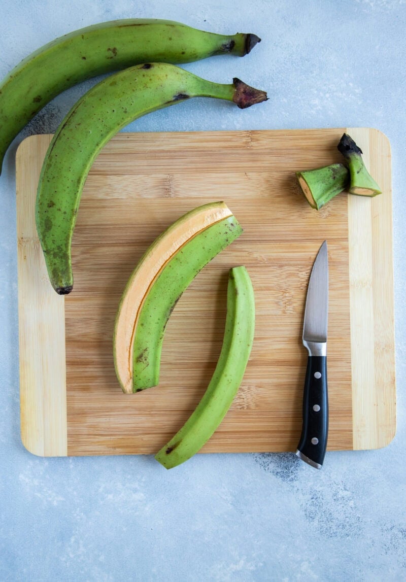Plátanos verdes siendo pelados a mano, listos para preparar unos buenos tostones caseros.