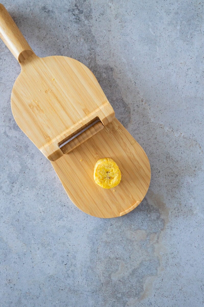 Después de la primera fritura, las rodajas de plátano se prensan suavemente para crear su forma clásica. Este paso es clave para lograr el equilibrio perfecto entre un exterior crujiente y un interior suave y tierno que hace que los tostones sean tan irresistibles.