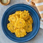 Tostones de freidora de aire servidos en un plato azul con sal marina.