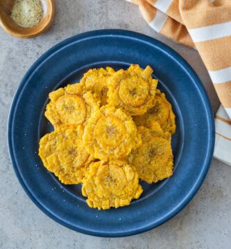 Tostones de freidora de aire servidos en un plato azul con sal marina.