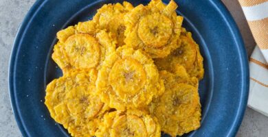 Tostones de freidora de aire servidos en un plato azul con sal marina.