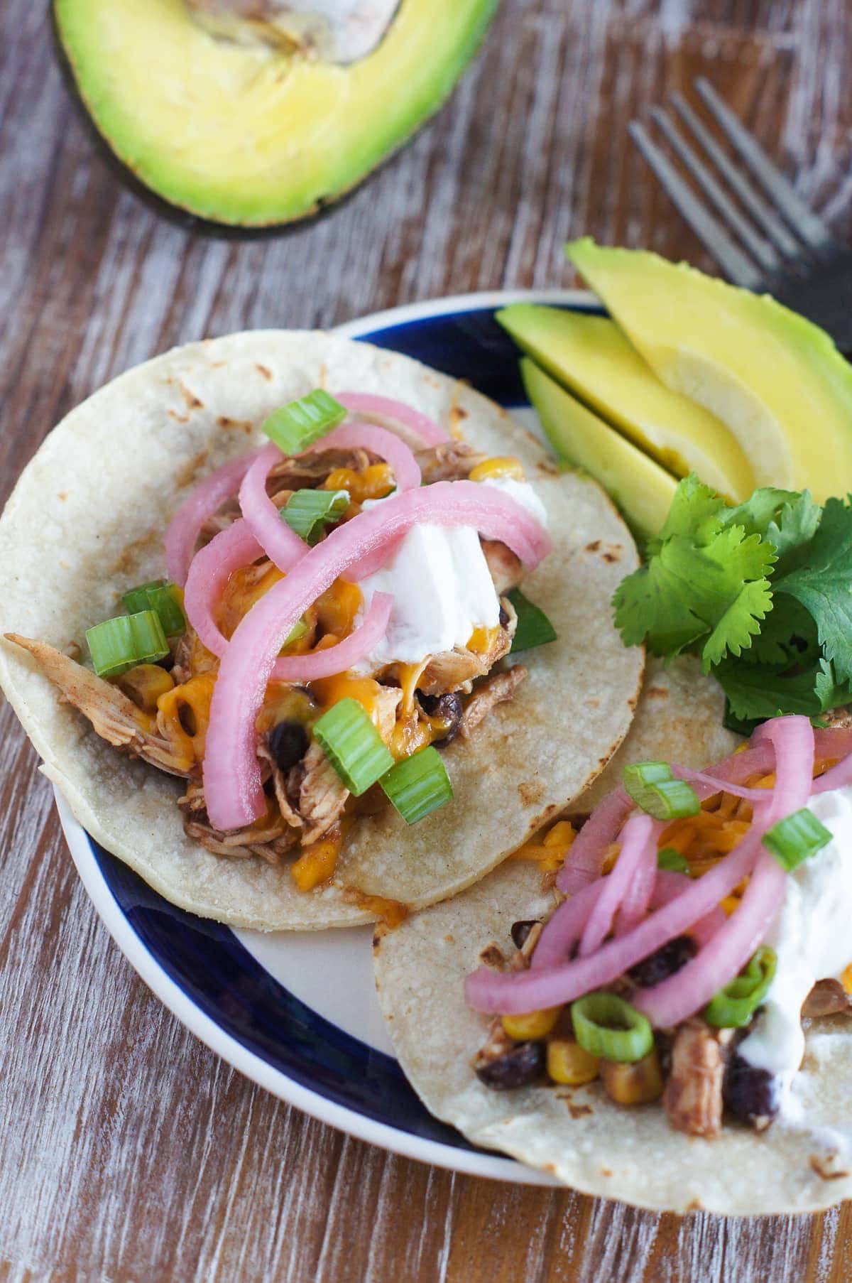 A chicken taco topped with pickled onions and sour cream.